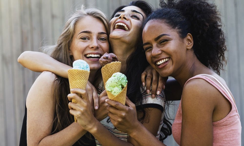 group of young girls holding ice cream and laughing
