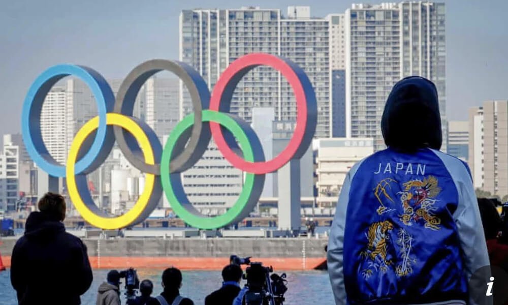 A crowd looking at a huge Olympic sign