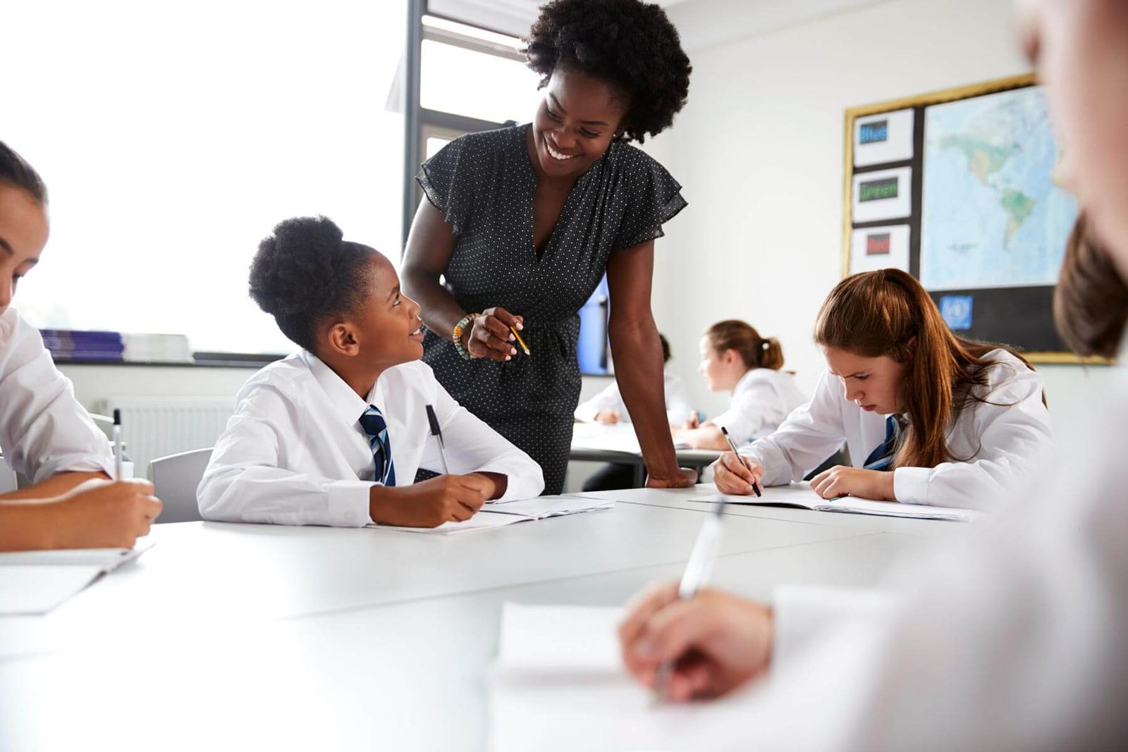 A female teacher is interacting with a female student in class